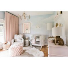 a baby's room with pink and white decor, including a crib, rocking chair, rugs, lamps, and pictures on the wall