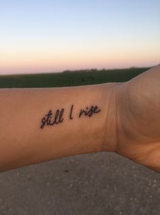 a person's arm with the word still i rise written on it in cursive font