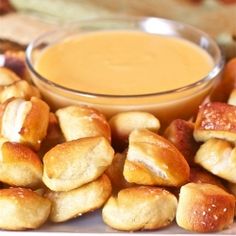 a white plate topped with mini pigs in a blanket next to a bowl of dipping sauce