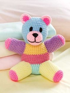 a crocheted teddy bear sitting on top of a bed