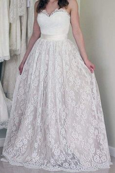 a woman standing in front of a mirror wearing a white dress with lace on it