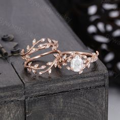 two wedding rings sitting on top of a wooden table next to each other with flowers and leaves