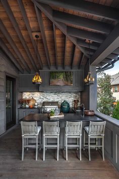 an outdoor kitchen and dining area on a wooden deck with white chairs around the table