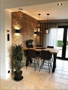 a dining room table and chairs in front of a brick wall with lights on it