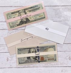 three envelopes and one dollar bill on a white wooden background with the word congratulations written in cursive writing