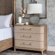 a bedroom scene with focus on the nightstand and bed side table, which has a vase with flowers on it