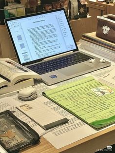 an open laptop computer sitting on top of a desk next to books and other items