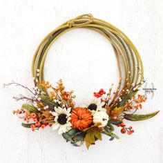 a wreath with flowers and leaves is hanging on the wall