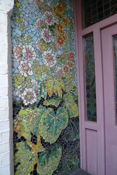 the front door is decorated with mosaic tiles and flowers on it's side wall