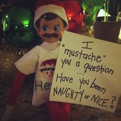 an elf holding a sign that says i mustache you a question have you been naught or nice?