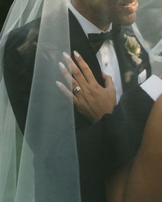 a bride and groom standing under a veil