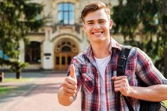 a young man is smiling and holding his thumb up