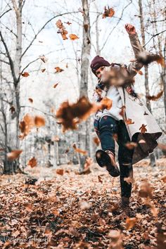 a woman is running through leaves in the woods