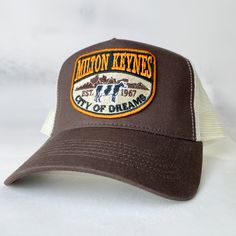 Milton Keynes City Of Dreams , Buckinghamshire - vintage style retro trucker cap - brand new. Condition is New with tags.  This is the brown version. The cap is wrapped in tissue paper and shipped in a rigid box so it'll arrive in perfect condition. Brilliant exclusive design, not available anywhere else. Great conversation starter and gift for residents of Milton Keynes. Retro Trucker Hat With Logo Patch, Retro Trucker Hat With Embroidered Logo, Brown Trucker Hat With Letter Print, Vintage 5-panel Trucker Hat With Logo Patch, Retro Brown Trucker Hat With Letter Print, Vintage Brown 5-panel Trucker Hat, Brown Trucker Baseball Cap With Letter Print, Vintage Brown Trucker Hat With Letter Print, Retro Curved Bill Hat With Logo Patch