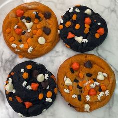 four cookies decorated with halloween candy and marshmallows on a white plate,