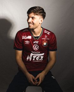 a man sitting on top of a chair wearing a red shirt