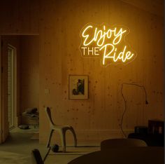 a neon sign that says enjoy the ride in front of a room with wooden walls