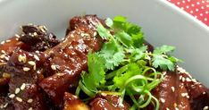 a white bowl filled with meat covered in sauce and garnished with cilantro