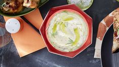 a table topped with plates filled with different types of dips and pita bread