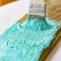 a paintbrush is being used to decorate a piece of wood with blue icing