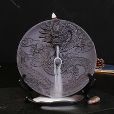 a plate with a dragon design on it and a lit candle in the middle next to it