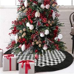 a christmas tree decorated with red, white and gold ornaments is sitting next to presents