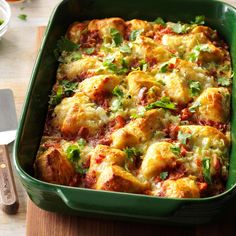 a green casserole dish filled with meat and cheese