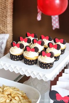 cupcakes with minnie mouse ears are on a cake platter next to other desserts