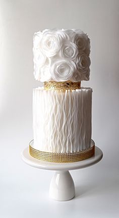 two tiered wedding cake with white frosting and gold trimmings on top