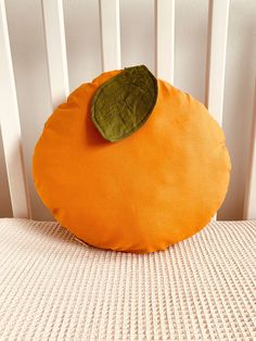 an orange pillow sitting on top of a white bed