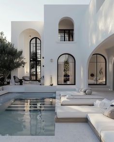 an outdoor living area with couches and a pool in front of a white building