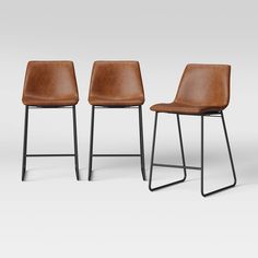 three brown leather chairs with black metal legs and backrests, side by side