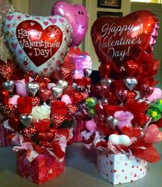 two valentine's day gifts are sitting on a table with balloons and heart - shaped candies