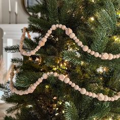 a christmas tree decorated with wooden beads and lights in the shape of a house on it