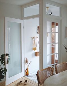 a dining room table and chairs in front of an open glass door with plants on the side