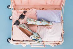 an open suitcase with clothes and shoes in it on a blue background, top view