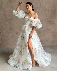 a woman in a white floral dress posing for the camera with her legs crossed and one leg up