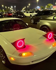 a white sports car with red lights on it's hood in a parking lot