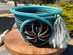 a close up of a blue bracelet with feathers on it and a flower in the center