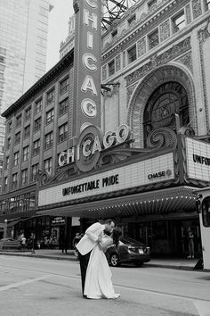 a bride and groom kissing in front of the chicago theatre