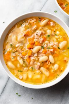 two bowls filled with white bean soup on top of a marble counter next to a spoon