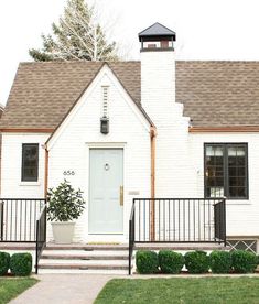 a white house with a black gate and steps leading up to the front door is shown