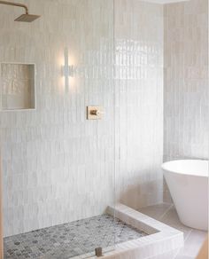 a white bath tub sitting next to a walk in shower under a bathroom light fixture