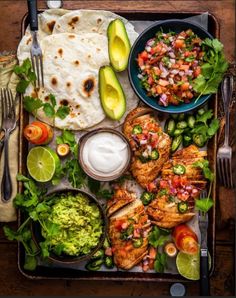 an overhead view of mexican food including chicken, guacamole and tortillas