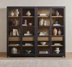 an open bookcase with vases and books on the shelves in front of it