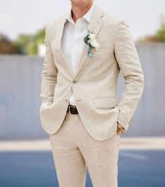 a man in a tan suit and flower boutonniere is posing for the camera