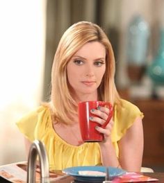 a woman sitting at a table holding a red cup