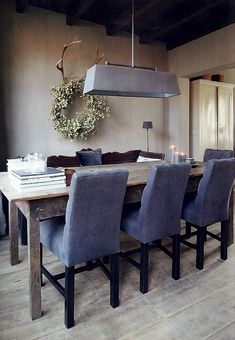 a dining room table with blue chairs and a wreath hanging from the ceiling over it