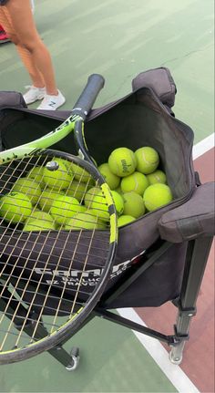 tennis balls and rackets are in a bag on the court