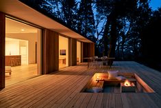 an outdoor fire pit is lit up at night on the deck outside with chairs and tables